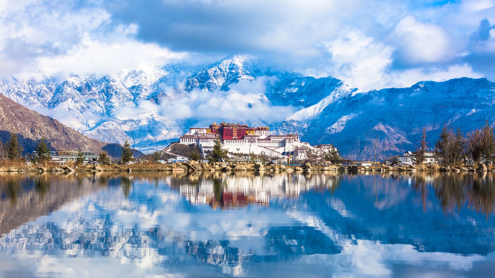 Panoramic view of Potala Palace in Tibet with snow-capped mountains and reflection in water, part of 30-Day China Tour.